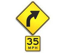 diamond-shaped yellow sign with arrow curving to upper right and "35 MPH" written on rectangular yellow sign below.